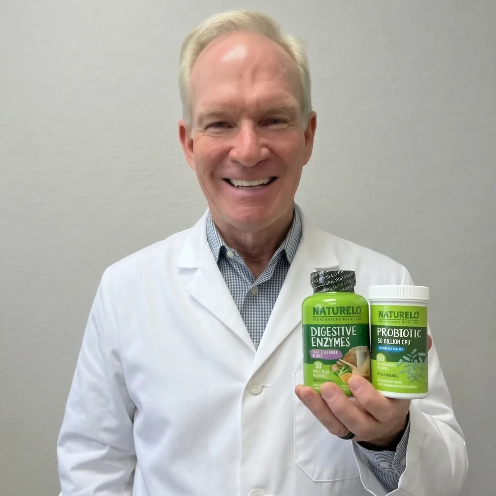 A physician in a white coat smiling and holding the NATURELO Digestive Enzymes and Probiotic 50 Billion CFU bottles in one hand.